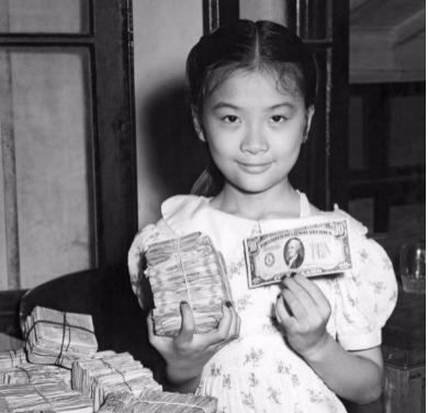 Girl in Shanghai holding US dollars which, while off the gold standard since 1933, were a beacon of stability versus the Chinese currency